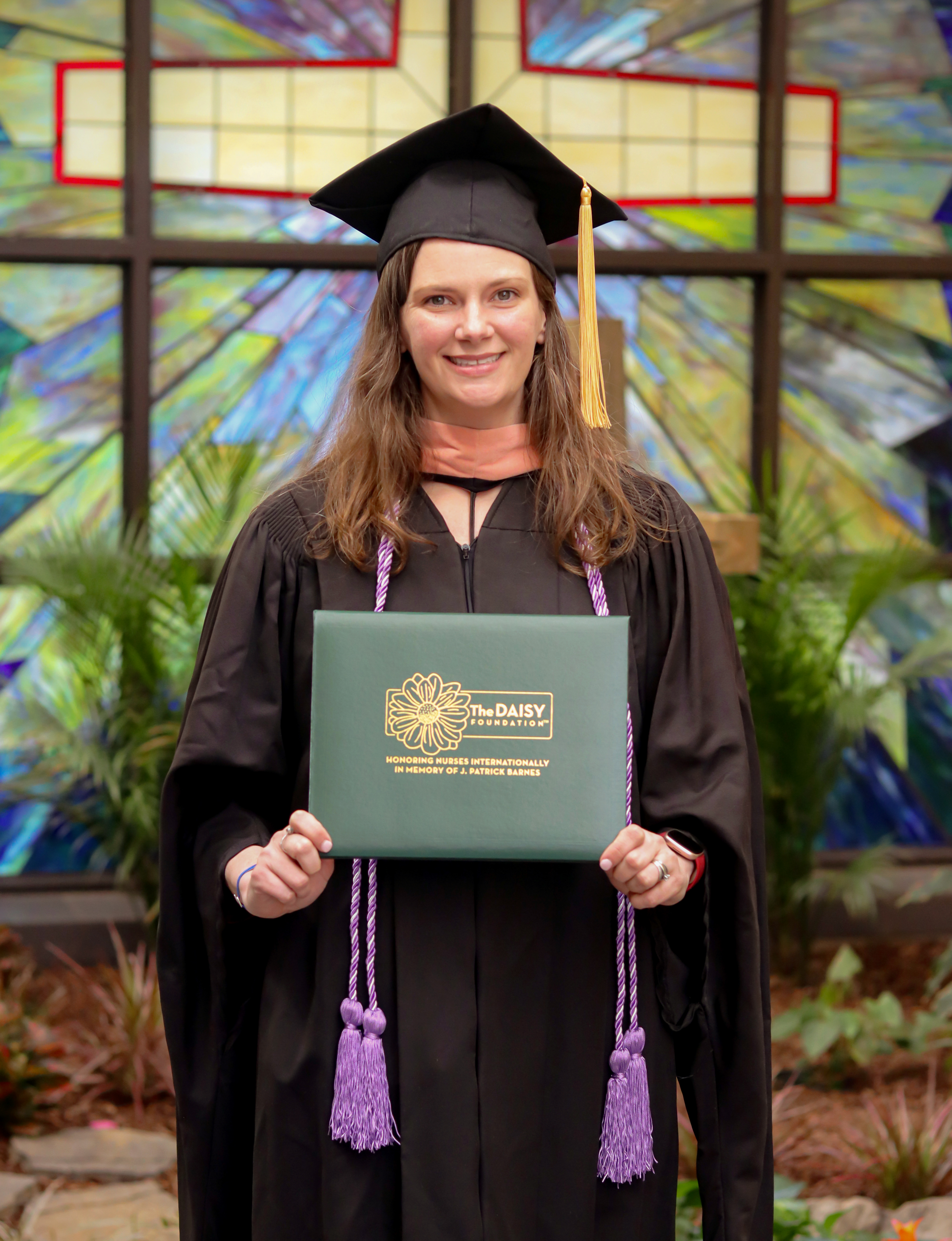 Allyson Smith holding DAISY award in front of a cross