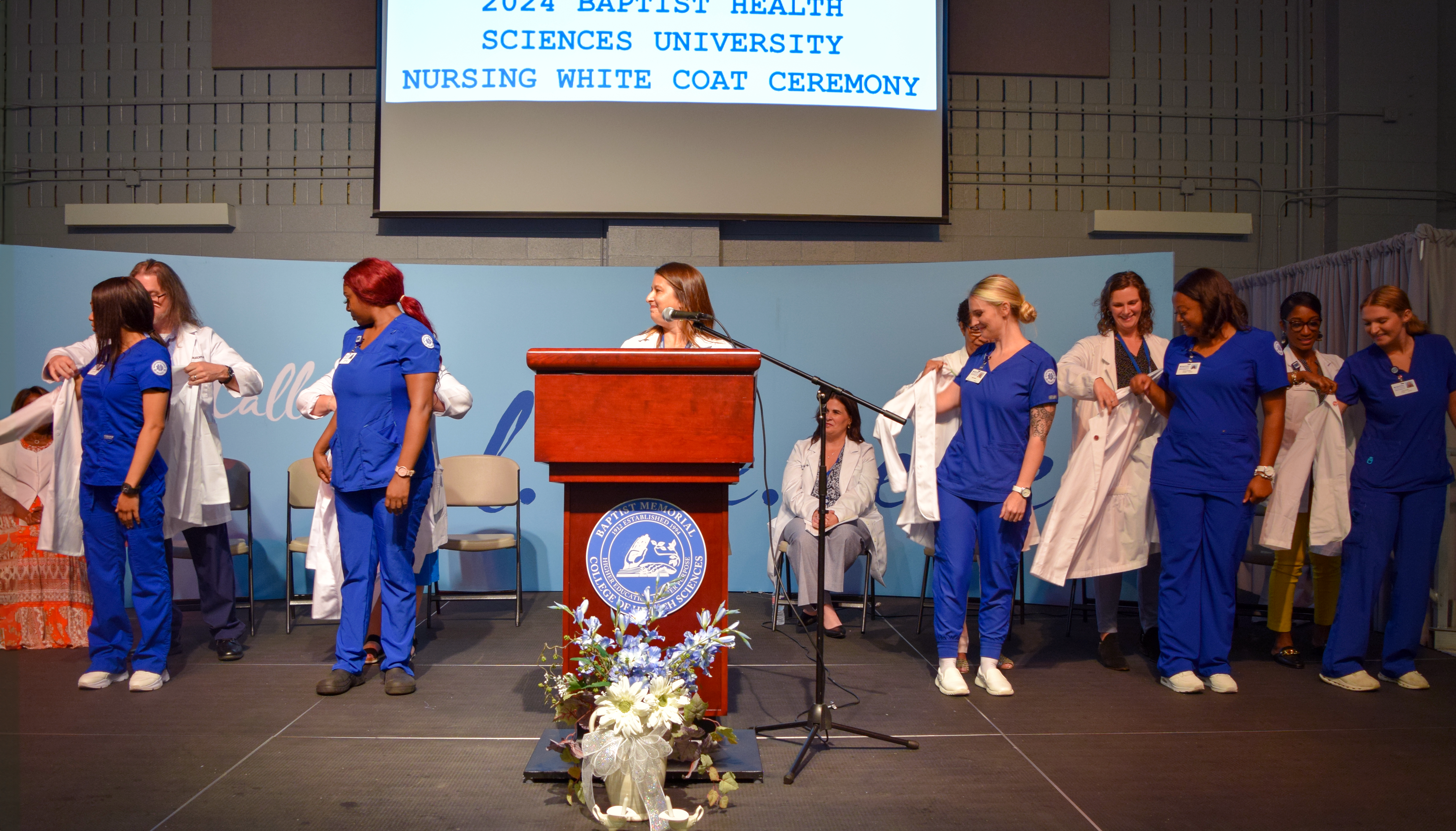 Five nursing students putting white coats on 