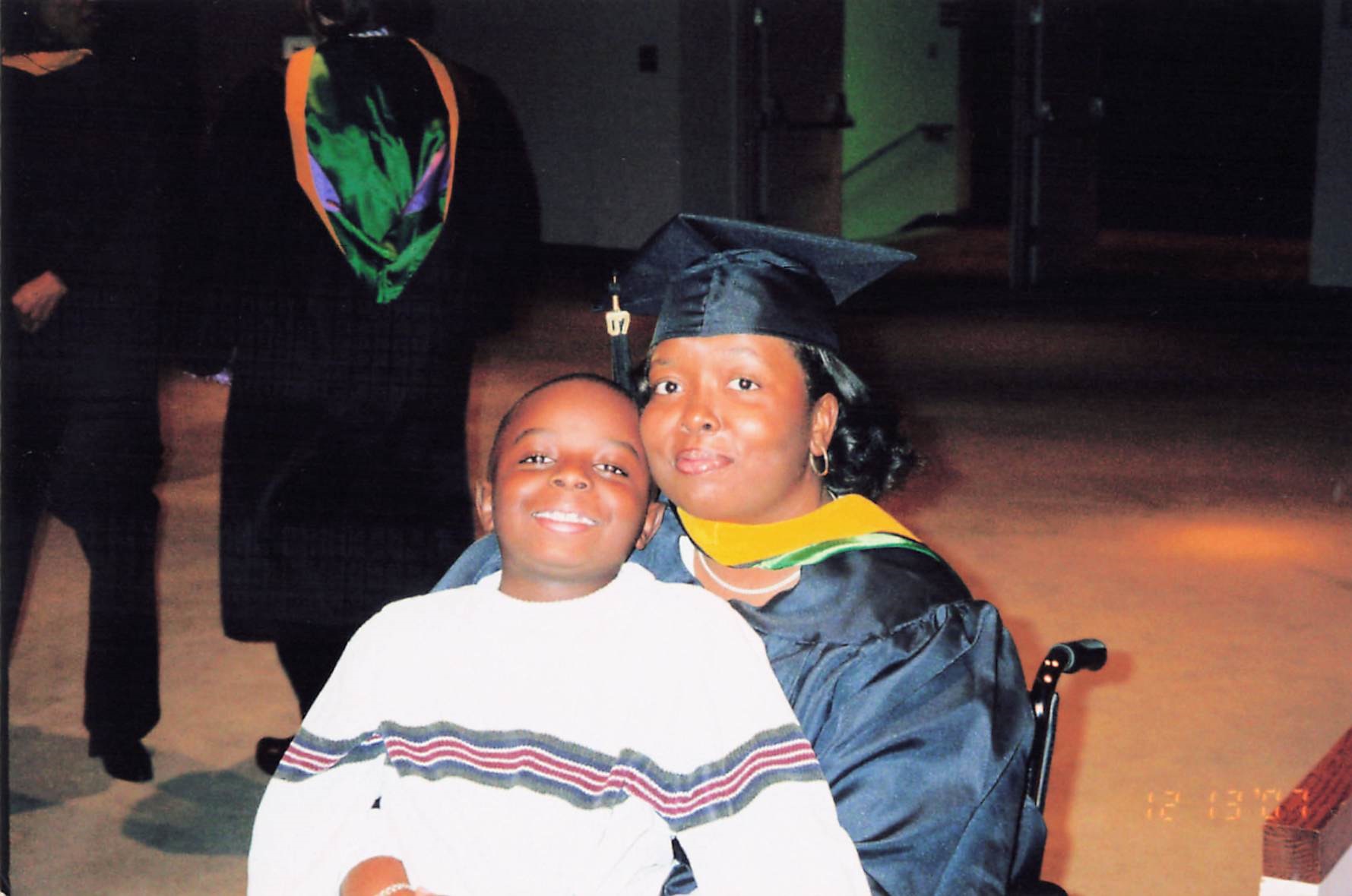 Photo of AJ with his mother at her graduation with him sitting in her lap.