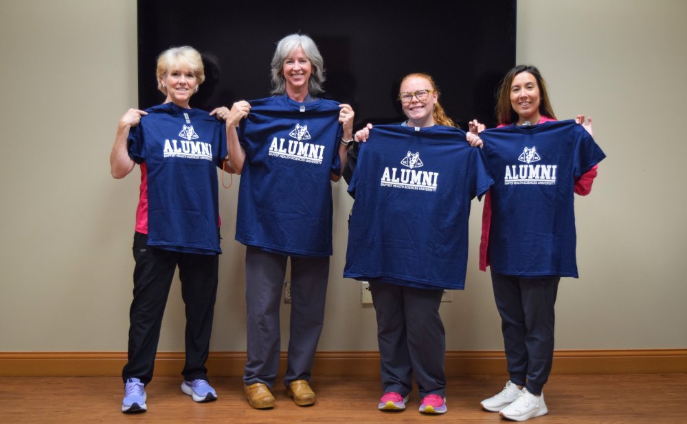 Group photo of Baptist Alumni holding Alumni t-shirts at lunch