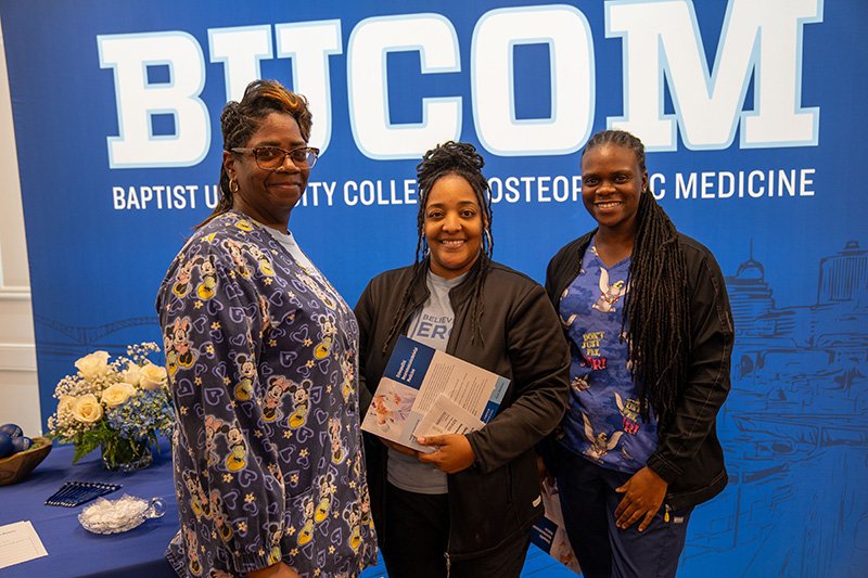 3 nurses in front of the BUCOM Backdrop 