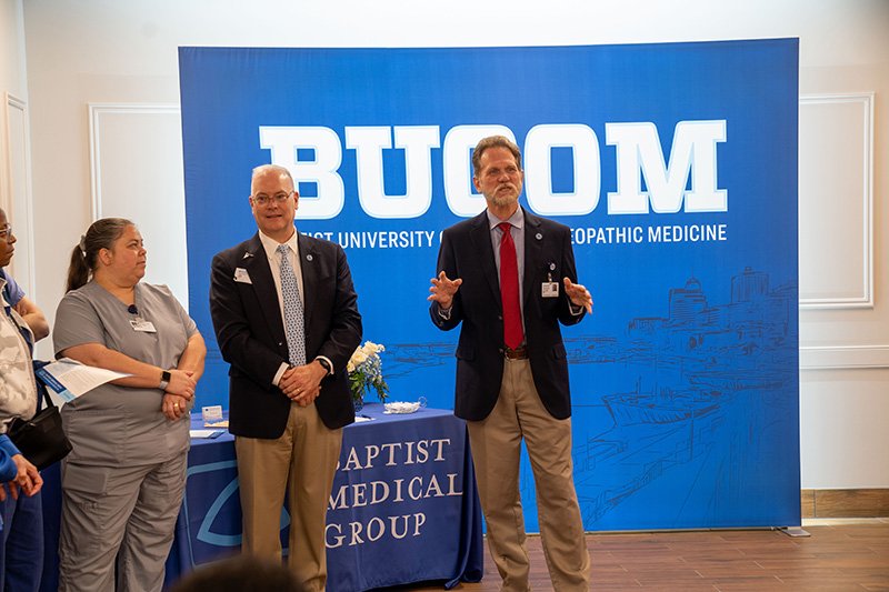 Dr. Bell addressing the crowd in front of the BUCOM sign