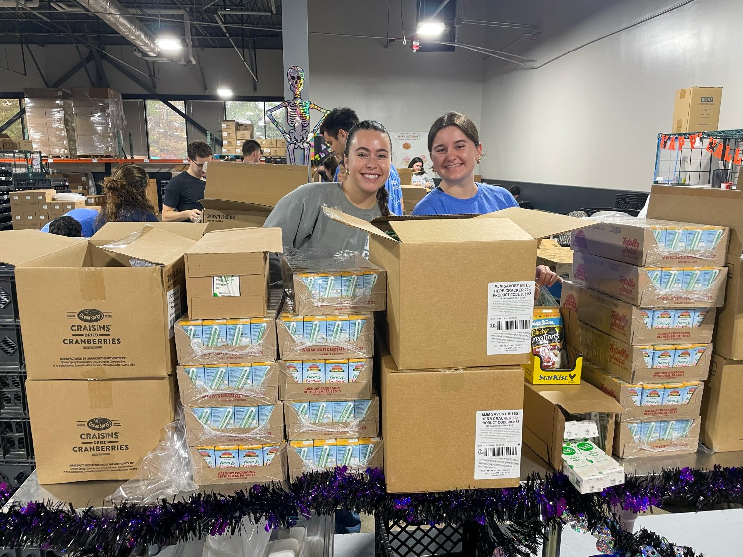 two students behind boxes packaging items behind boxes 