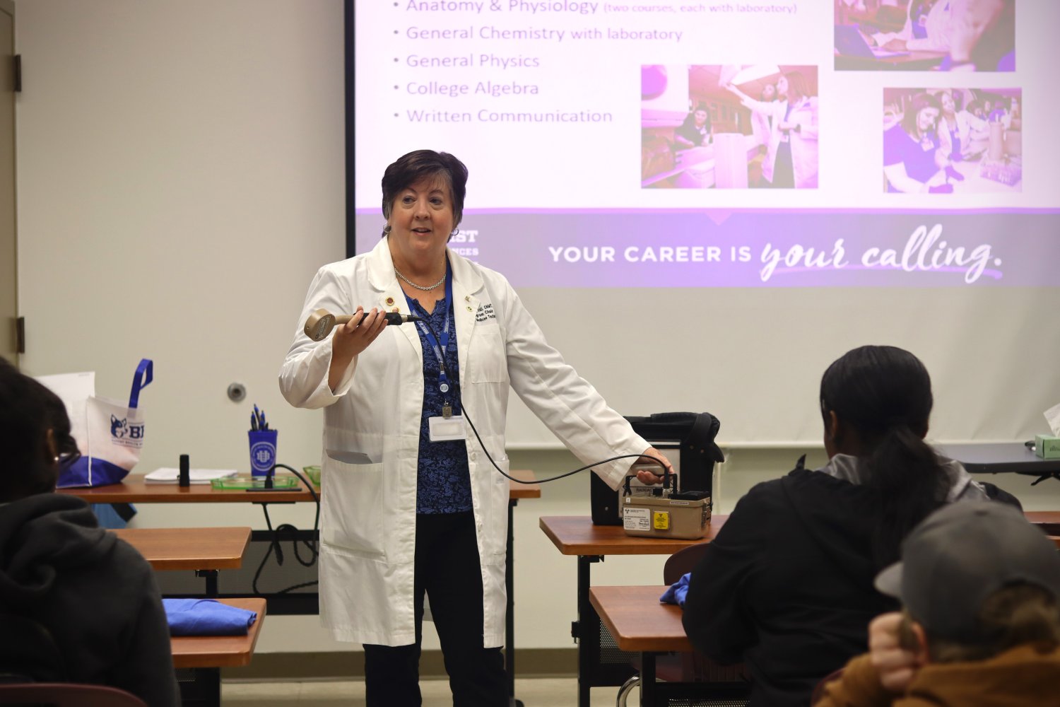 Donna Mars holding a nuclear medicine tool in front of the students