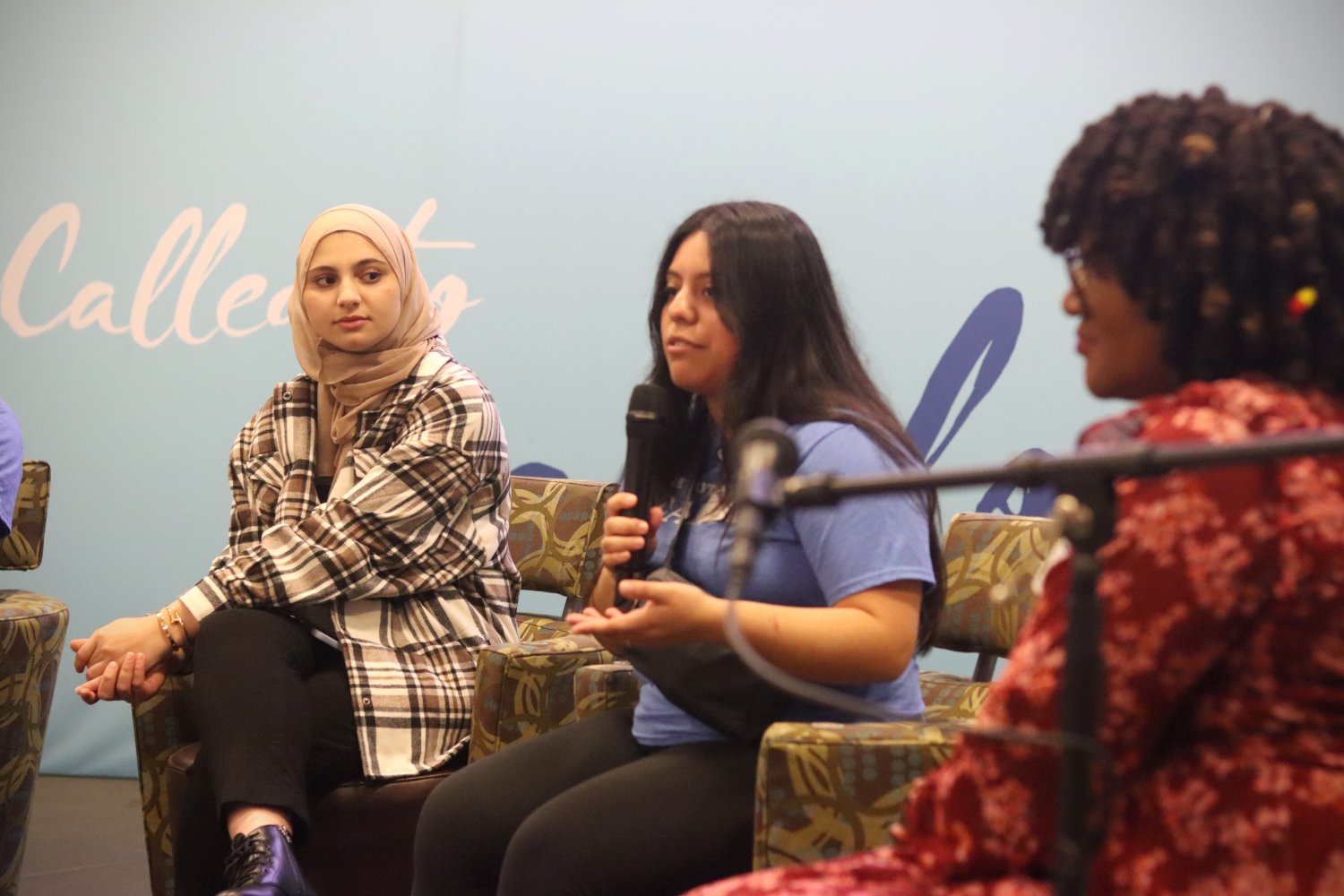 two students and one professor. One student speaking with a microphone