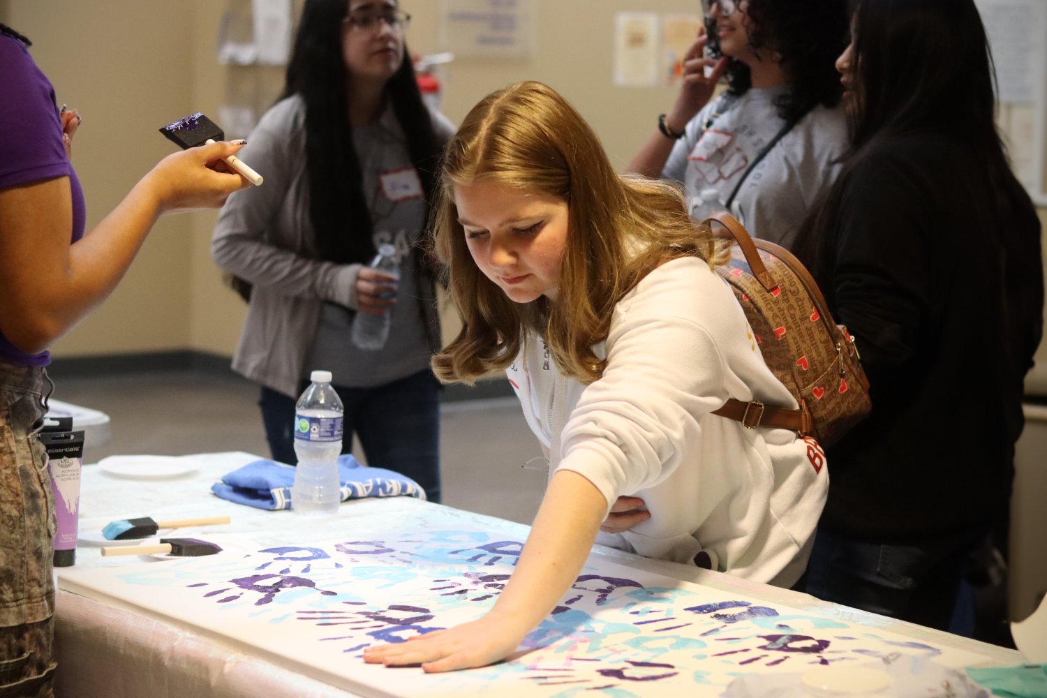 One student on a hand painting for cancer awareness