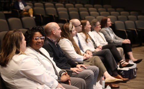 One DNP student looking toward camera while the rest is faced towards the stage 